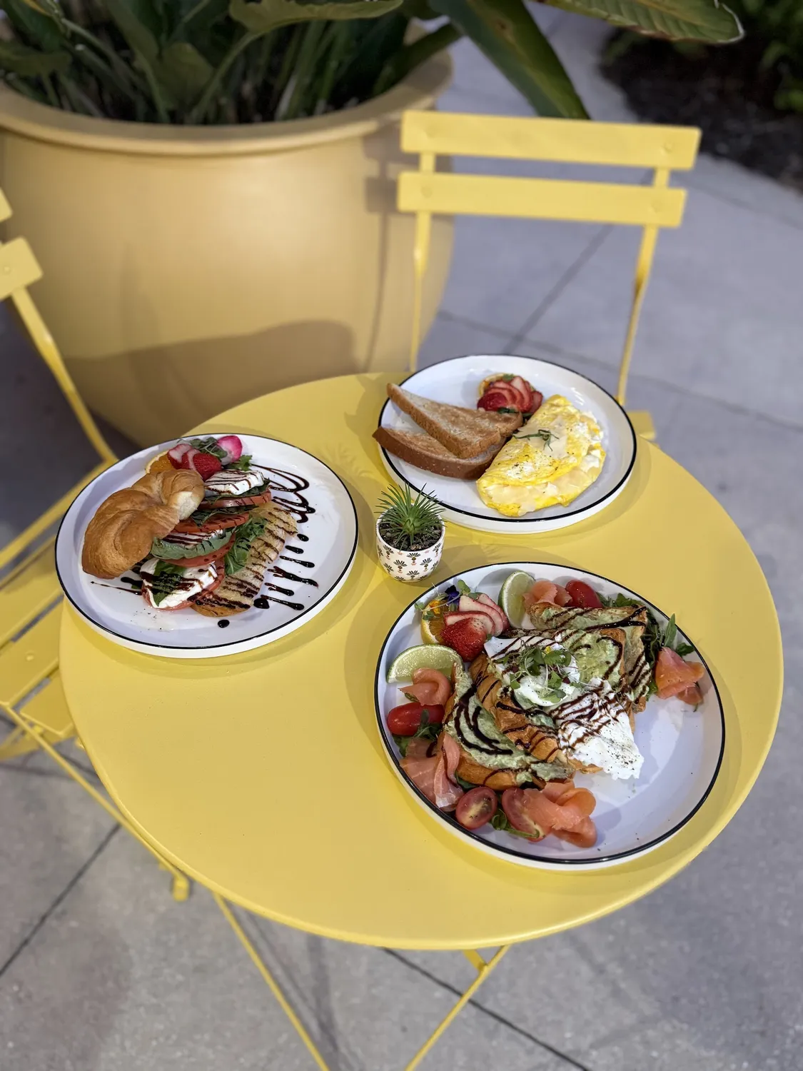 Brunch plates on a yellow patio table at Alba